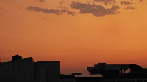 Golden twilight sky with clouds over city building silhouettes at sunset. 스톡 동영상 339077715