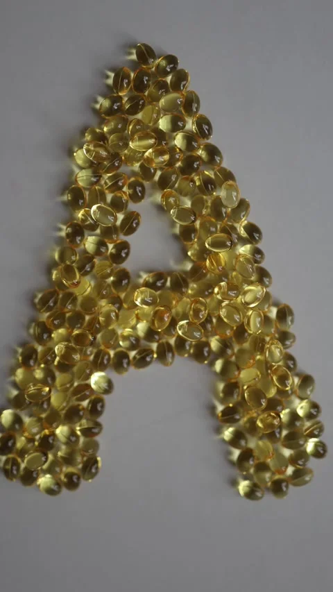 Golden vitamin A softgel capsules create a large letter A Vidéo 342610237