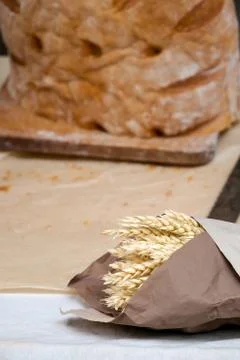 Golden wheat ears wrapped in craft paper and loaf of rustic whole grain bread Stock Photos