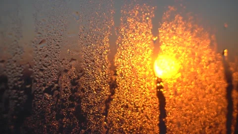 Golden winter sunlight shining through a foggy window pane with water droplets 動画素材 342212035