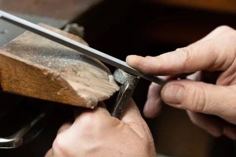 Goldsmith sands a silver ring on the workbench. Stock Photos