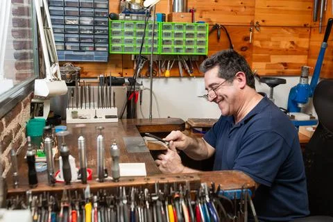 Goldsmith sands a silver ring on the workbench. Stock Photos