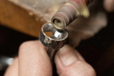 Goldsmith sands a silver ring on the workbench. Stock Photos