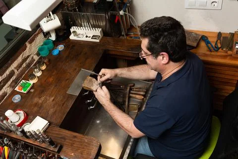 Goldsmith sands a silver ring on the workbench. Stock Photos