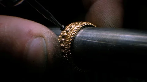Goldsmith using a drill tool to make a hole in golden ring. Jeweler is drilling Stock Footage 124083968