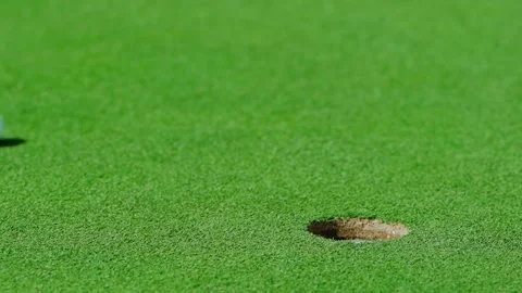 A golf ball after being hit by a club flies across the lawn into the hole Stock Footage 213718439