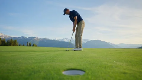 Golf Ball Drops Into Cup on Alpine Green in Verbier Video stock 337603255