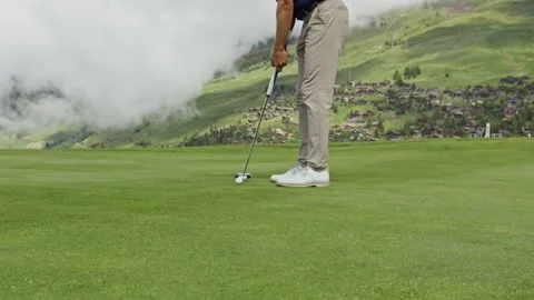 Golf Ball Drops Into Cup on Mountain Green in Verbier Video stock 337603555