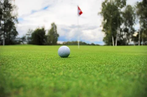 Golf ball in front of flag 库存照片