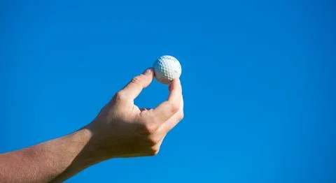 Golf ball held in hand against the blue sky golf concept Stock Photos