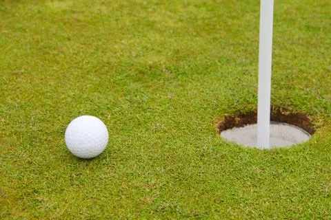 Golf ball on lip of cup 스톡 사진