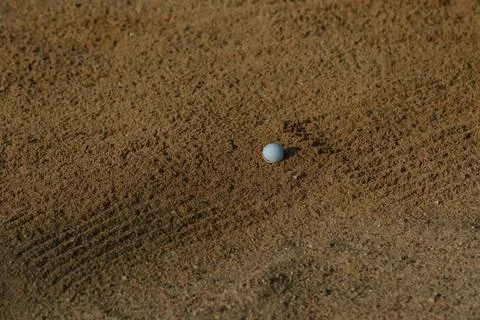 Golf ball resting on sand in a golf course bunker, highlighting the challenge Stock Photos