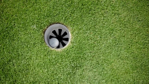 Golf ball rolling into hole Stock Footage