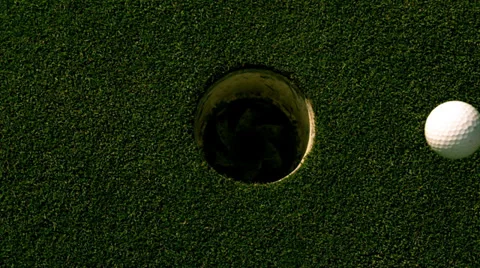 Golf ball rolling into the hole on putting green Stock Footage 39671842