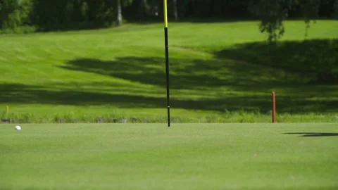 Golf ball rolls past the flag in the hole 库存影片 155363412