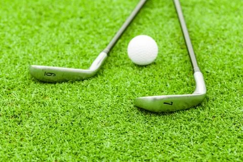 Golf ball on tee in front of driver on green course Stock Photos