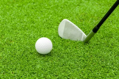 Golf ball on tee in front of driver on green course Stock Photos