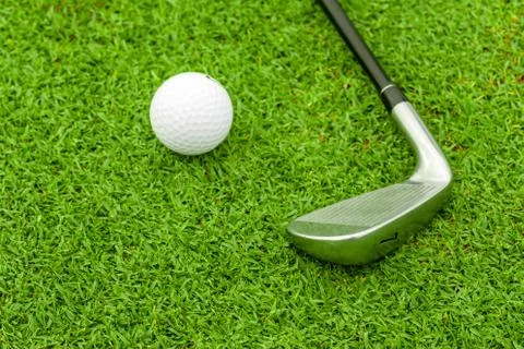Golf ball on tee in front of driver on green course Stock Photos