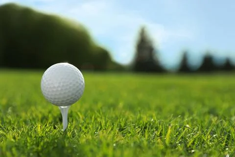 Golf ball on tee at green course, space for text Stock Photos