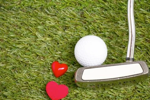 Golf ball with two hearts and putter of golfer are on green grass Stock Photos