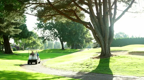 A golf cart comes around the corner on the golf cart path Stock Footage
