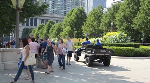 Golf cart passes pedestrians in Millenium Park in Chicago 動画素材 43128892