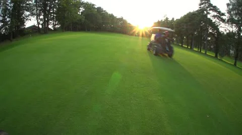 Golf Cart rides on fairway into sunset Stock Footage