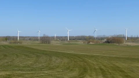 Golf course and some wind turbines - green meadow, blue sky Stock Footage 106706947
