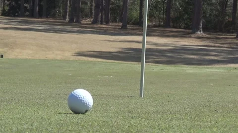 Golf course green with golf ball slowly rolling towards and going into cup In HD Stockbeeldmateriaal 61213348