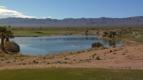 Golf course inside desert mountains surrounds a pond A Stock Footage 125344185