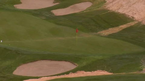 Golf course putting green sits inside red desert rocks and sand B Stock Footage 125344273