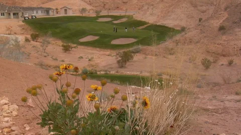 Golf course putting green sits inside red desert rocks and sand C Stock Footage 125344280