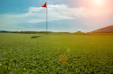 Golf course with red flag and sun flare Stock Photos