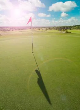 Golf course with red flag and sun flare Stock Photos