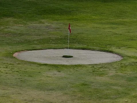 A Golf Course Sand Trap featuring a Flag represents the essence of the golf.. Stock Photos