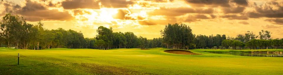 Golf course at sunset with dramatic sky and sand trap. Picturesque panoramic Stock Photos