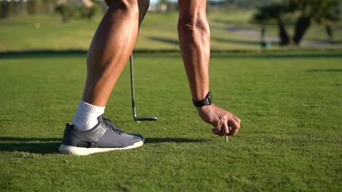 Golf course turf. Hands of an older man place a tee and a golf ball on the .. Stock Footage 252603884