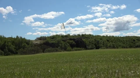 Golf course with a white flag on the putting green waving in the wind on a Stock Footage 346326316