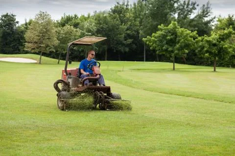 Golf course worker mows the grass of a green Stock Photos
