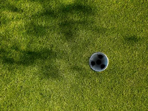Golf Grass &amp; Hole with tree shadows. Stock Photos