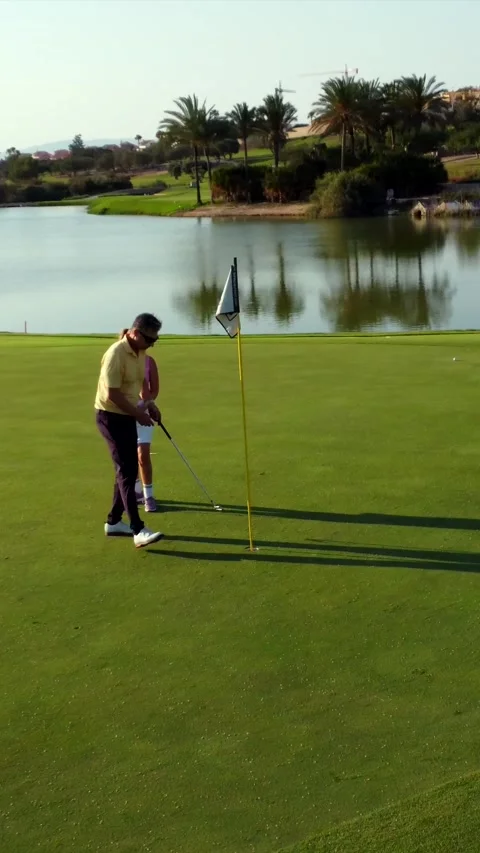 Golf instructor assisting woman putting on green Stock Footage 315364737