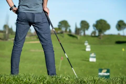 Golf player with cap leaning on a golf club looking at the course Stock Photos