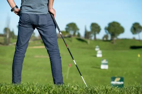 Golf player with cap leaning on a golf club looking at the course Stockfoto's