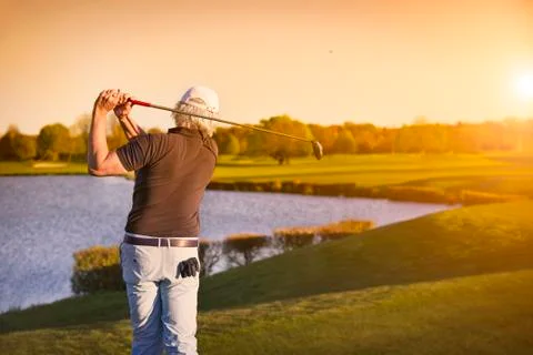 Golf player teeing off at sunset. Stock Photos