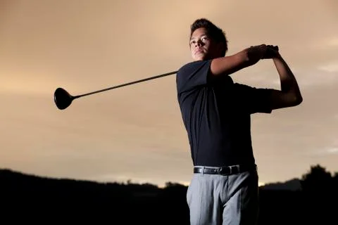 Golf player teeing off at sunset. Stock Photos