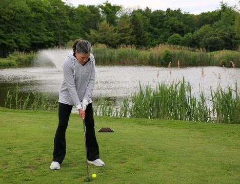 Golf Practice Session by the Serene Pond in a Lush Park Setting Stockfoto's