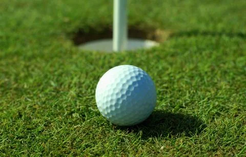 Golfball in front of the hole Stock Photos