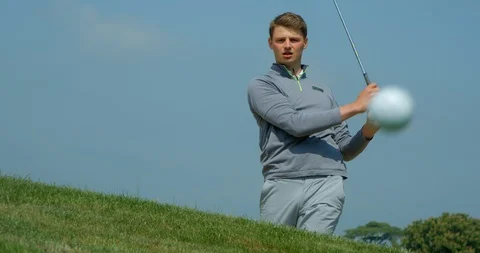 A Golfer chips out of a sand trap in slow motion with ball bouncing into frame. Vídeo Stock 101643620