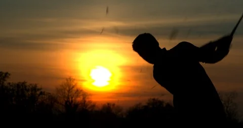 A Golfer chips a shot at sunset with a large divot flying through the air. Vídeo Stock 103589106
