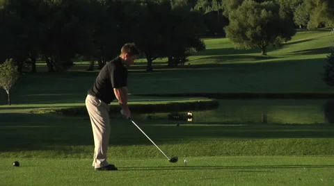 Golfer drives ball as camera tilts up. Stock Footage 46594230